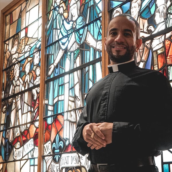 Fr. Henry Torres in front of stained glass window